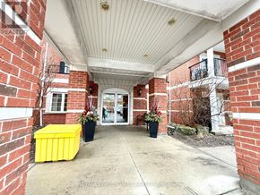Clarington (Bowmanville) condo for rent - A red brick building with a white roof and a yellow planter box.