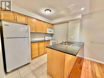 Clarington (Bowmanville) condo for rent - A kitchen with wooden cabinets and a white fridge.