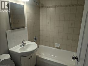 Hamilton condo for rent - A white sink and bathtub in a bathroom with a mirror above the sink.