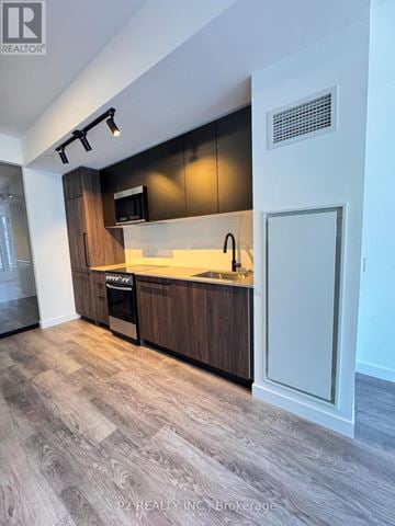 Toronto (Centennial Scarborough) condo for rent - A modern kitchen with dark wood cabinets and a white countertop.