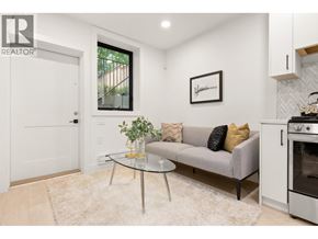 Vancouver apartment for rent - A living room with a grey couch, a glass table, and a framed picture on the wall.