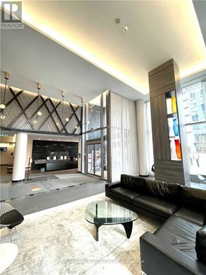 Toronto (Henry Farm) condo for rent - A black leather couch sits in a modern living room with a glass coffee table.