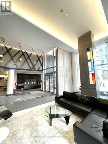 Toronto (Henry Farm) condo for rent - A black leather couch sits in a modern living room with a glass coffee table.