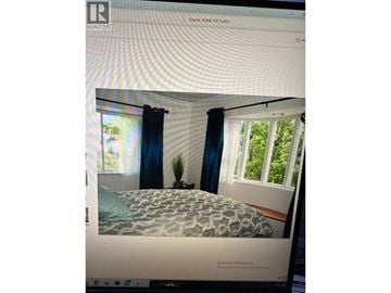 Vancouver apartment for rent - A bedroom with a bed, a window with blue curtains, and a plant on the windowsill.