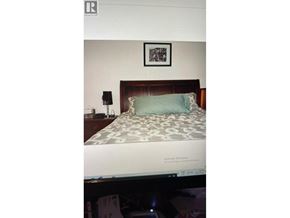 Vancouver apartment for rent - A bed with a green pillow and a picture frame on the wall.