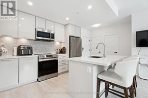 Innisfil condo for rent - A modern kitchen with white cabinets and stainless steel appliances.