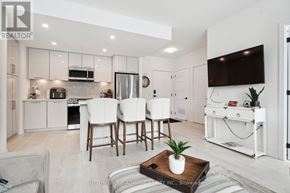 Innisfil condo for rent - A modern kitchen with white cabinets and a dining area with white chairs.