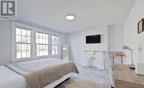London East (East F) fourplex for rent - A bedroom with a bed, fireplace, and a television.