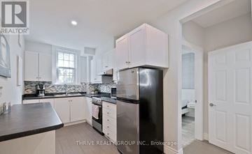 London East (East F) fourplex for rent - A kitchen with white cabinets and a black countertop.
