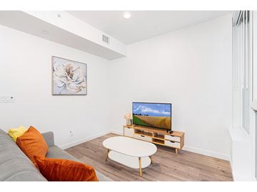 Surrey apartment for rent - A living room with a grey couch, a white coffee table, and a television on a wooden stand.