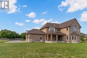 Whitchurch-Stouffville (Ballantrae) apartment for rent - A large brick house with a lawn in front and a sign that says "ON THE BLOCK, Brokerage".