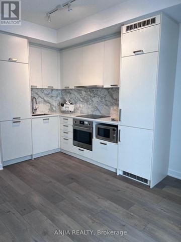 Vaughan (Vaughan Corporate Centre) condo for rent - A kitchen with white cabinets and a marble backsplash.