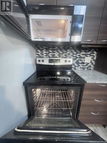 Waterloo condo for rent - A black oven with the door open is in a kitchen.