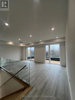 St. Catharines (Oakdale) townhouse for rent - A spacious room with a glass staircase and wooden flooring.