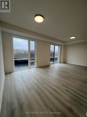 St. Catharines (Oakdale) townhouse for rent - A room with wooden flooring and a large window overlooking a field.