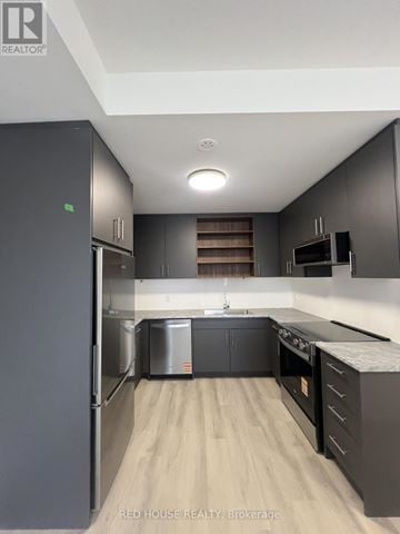 St. Catharines (Oakdale) townhouse for rent - A modern kitchen with dark wood cabinets and a refrigerator.