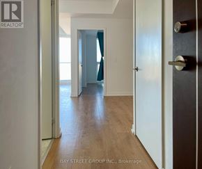 Toronto (Bayview Village) condo for rent - A hallway with wooden floors and white walls leading to a blue door.