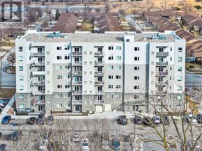 Windsor condo for rent - A large apartment building with a parking lot in front.
