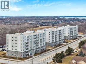 Windsor condo for rent - A large apartment complex is situated on a street with a view of a town in the distance.