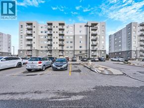 Windsor condo for rent - A parking lot with cars and apartment buildings in the background.