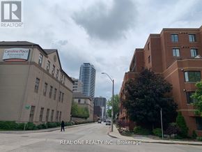Hamilton (Central) condo for rent - A street view of a residential area with apartment buildings and a sign for Caroline Place Retirement.