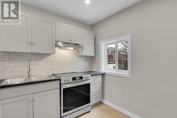 Ottawa duplex for rent - A kitchen with white cabinets and a black stove top oven.
