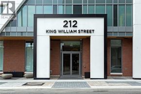 Hamilton condo for rent - The front of a building with a glass facade and a sign that reads "212 King William Street.".