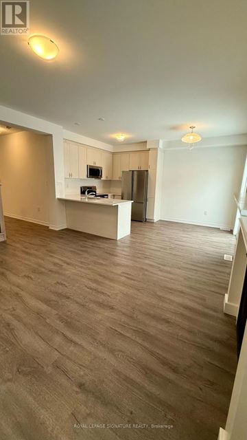 Milton (Bw Bowes) townhouse for rent - A spacious living room with a kitchenette in the background.