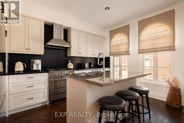 Toronto (Kingsway South) townhouse for rent - A kitchen with white cabinets and black countertops.