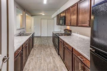 Post Falls apartment for rent - A kitchen with wooden cabinets and a black refrigerator.