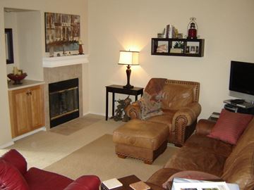 Spokane Valley apartment for rent - A living room with a fireplace, two chairs, a coffee table, and a painting on the wall.