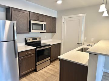 Post Falls apartment for rent - A kitchen with brown cabinets and a stainless steel refrigerator.