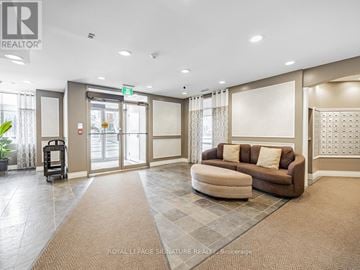 Toronto (High Park North) condo for rent - A spacious living room with a brown sofa and a large window with curtains.