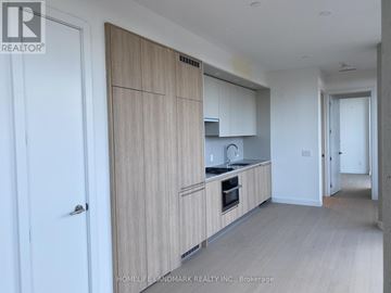 Toronto (Church-Yonge Corridor) condo for rent - A kitchen with wooden cabinets and a white door.