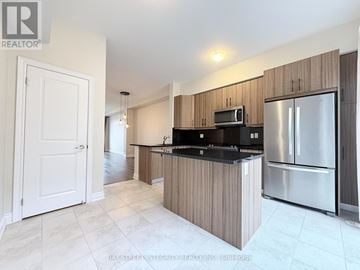 Oakville (Ro River Oaks) townhouse for rent - A kitchen with wooden cabinets and a stainless steel refrigerator.