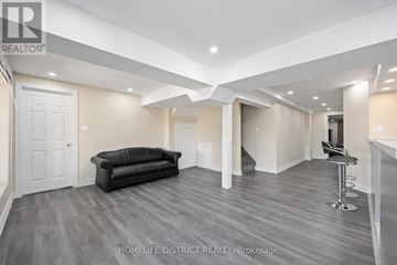 Ajax (Northeast Ajax) apartment for rent - A spacious living room with a black leather couch and a bar stool.