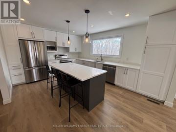 Prince Edward County (Wellington Ward) apartment for rent - A modern kitchen with a central island and stainless steel appliances.