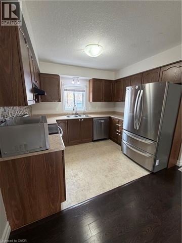 Kitchener townhouse for rent - A kitchen with a refrigerator, sink, and cabinets.