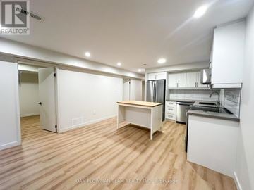 Oshawa (Taunton) apartment for rent - A kitchen area with a table and a refrigerator.