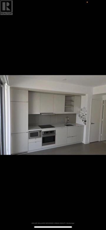 Toronto (Waterfront Communities) condo for rent - A modern kitchen with white cabinets and a black countertop.