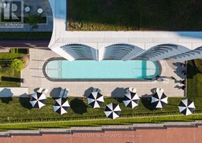 Toronto (Waterfront Communities) condo for rent - An aerial view of a pool surrounded by umbrellas and a building with the logo "TR" on it.