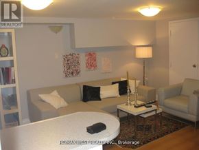 Toronto (Oakwood Village) fourplex for rent - A living room with a couch, a table, and a lamp.
