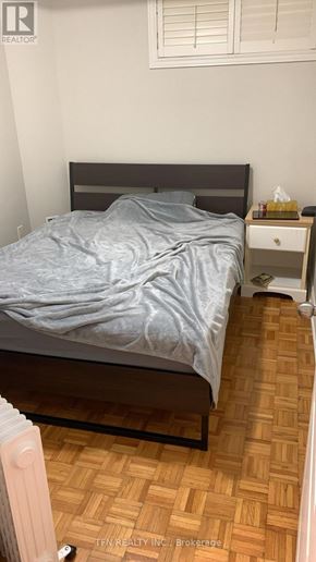 Toronto (Oakwood Village) apartment for rent - A bedroom with a bed, nightstand, and a wooden floor.