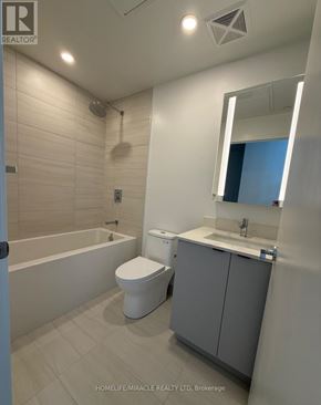 Toronto (South Parkdale) condo for rent - A bathroom with a white toilet, sink, and bathtub.