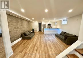 Toronto (The Beaches) multi-family for rent - A spacious living room with wooden flooring and a brick wall.