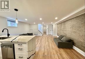 Toronto (The Beaches) multi-family for rent - A well-lit kitchen with wooden floors and a brick wall.