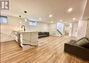 Toronto (The Beaches) multi-family for rent - A living room with a kitchen area in the background.