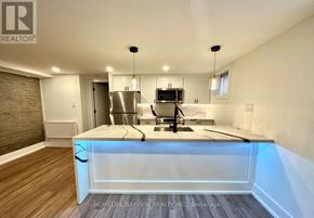 Toronto (The Beaches) multi-family for rent - A modern kitchen with a wooden floor and white walls.