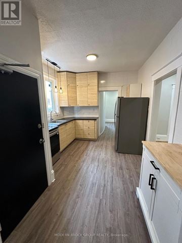Ottawa triplex for rent - A kitchen with a black refrigerator and wooden cabinets.