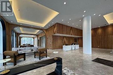 Toronto (Bayview Village) condo for rent - A spacious living room with a long white sofa and a black and white rug.